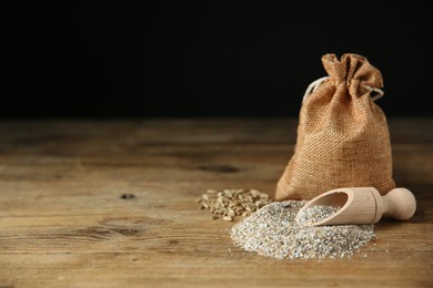 Photo of Pile of fresh rye bran, scoop and sack on wooden table. Space for text