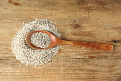 Photo of Pile of fresh rye bran and spoon on wooden table, top view