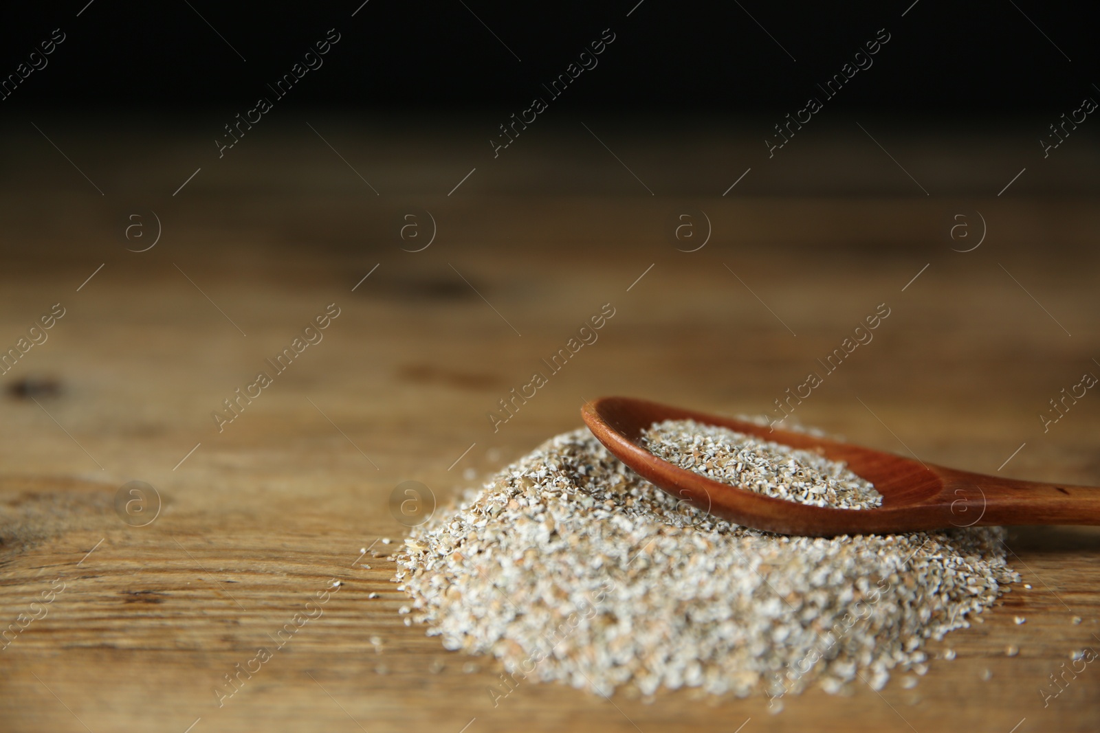 Photo of Pile of fresh rye bran and spoon on wooden table, closeup. Space for text