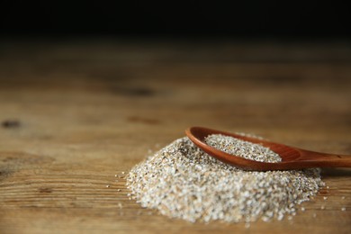 Photo of Pile of fresh rye bran and spoon on wooden table, closeup. Space for text