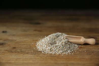 Photo of Pile of fresh rye bran and scoop on wooden table. Space for text