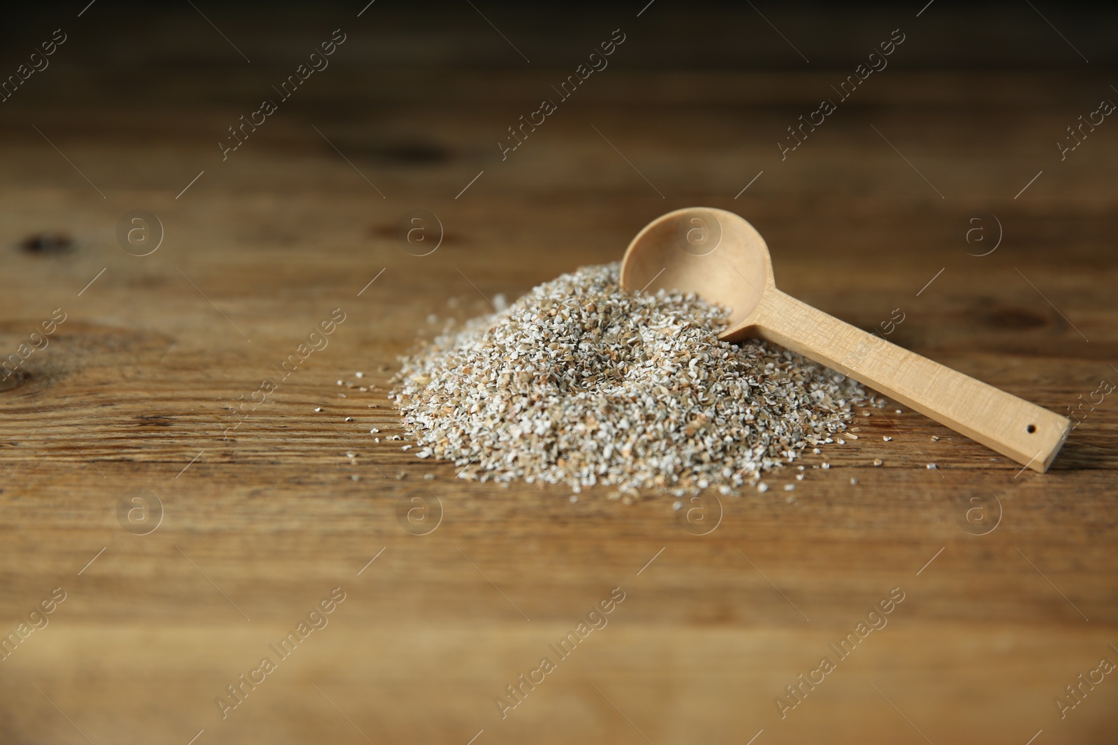 Photo of Pile of fresh rye bran and spoon on wooden table. Space for text