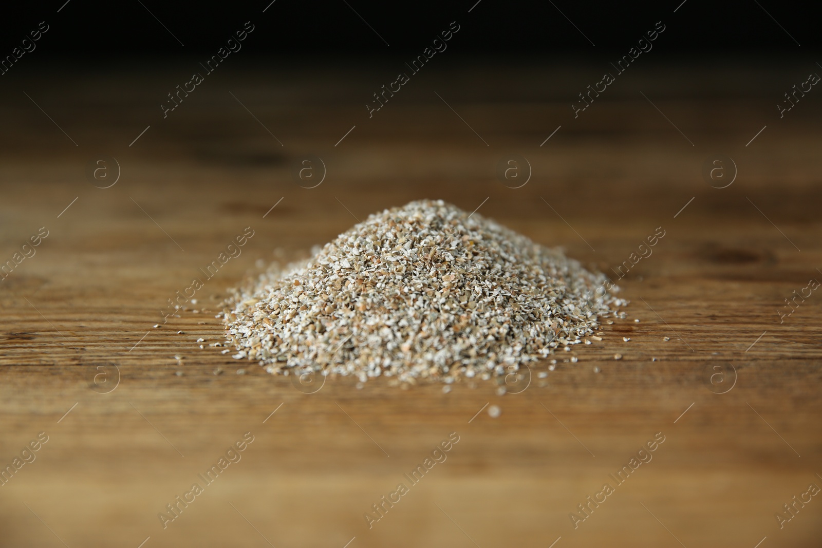 Photo of Pile of fresh rye bran on wooden table, closeup