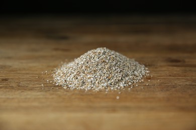 Photo of Pile of fresh rye bran on wooden table, closeup