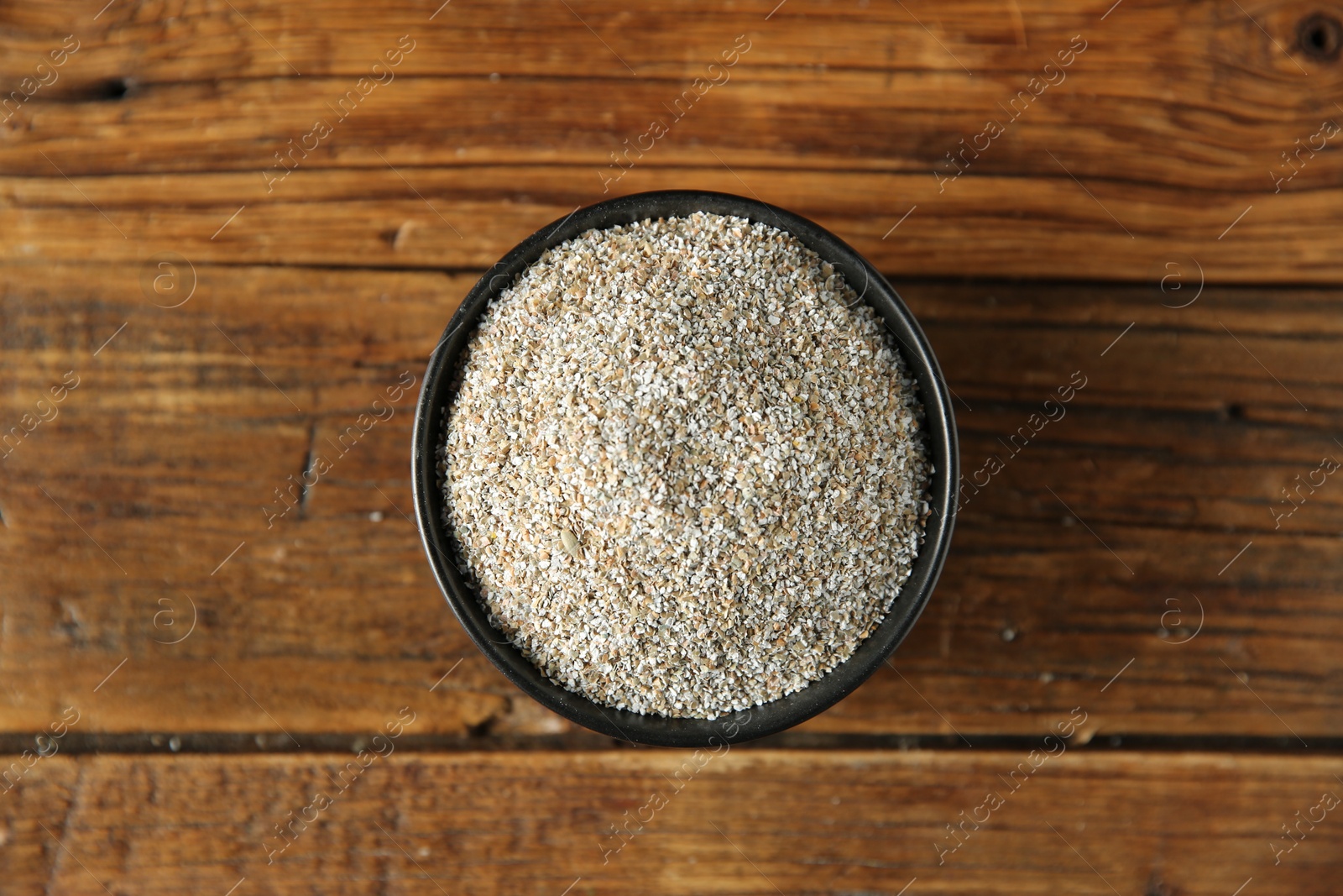 Photo of Fresh rye bran in bowl on wooden table, top view