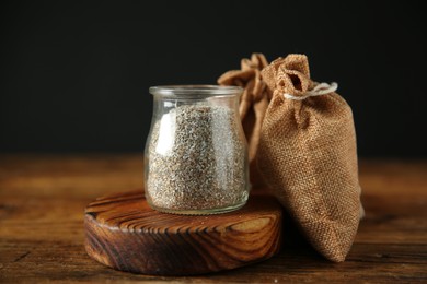 Photo of Fresh rye bran in jar and sack on wooden table, closeup