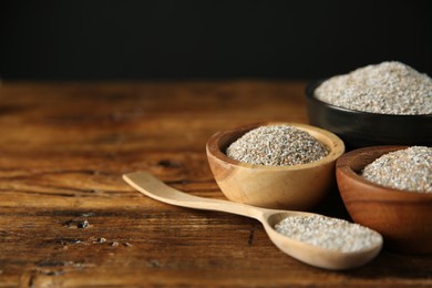 Fresh rye bran in bowls and spoon on wooden table, closeup. Space for text