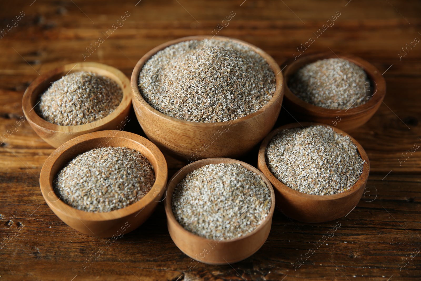 Photo of Fresh rye bran in bowls on wooden table, closeup