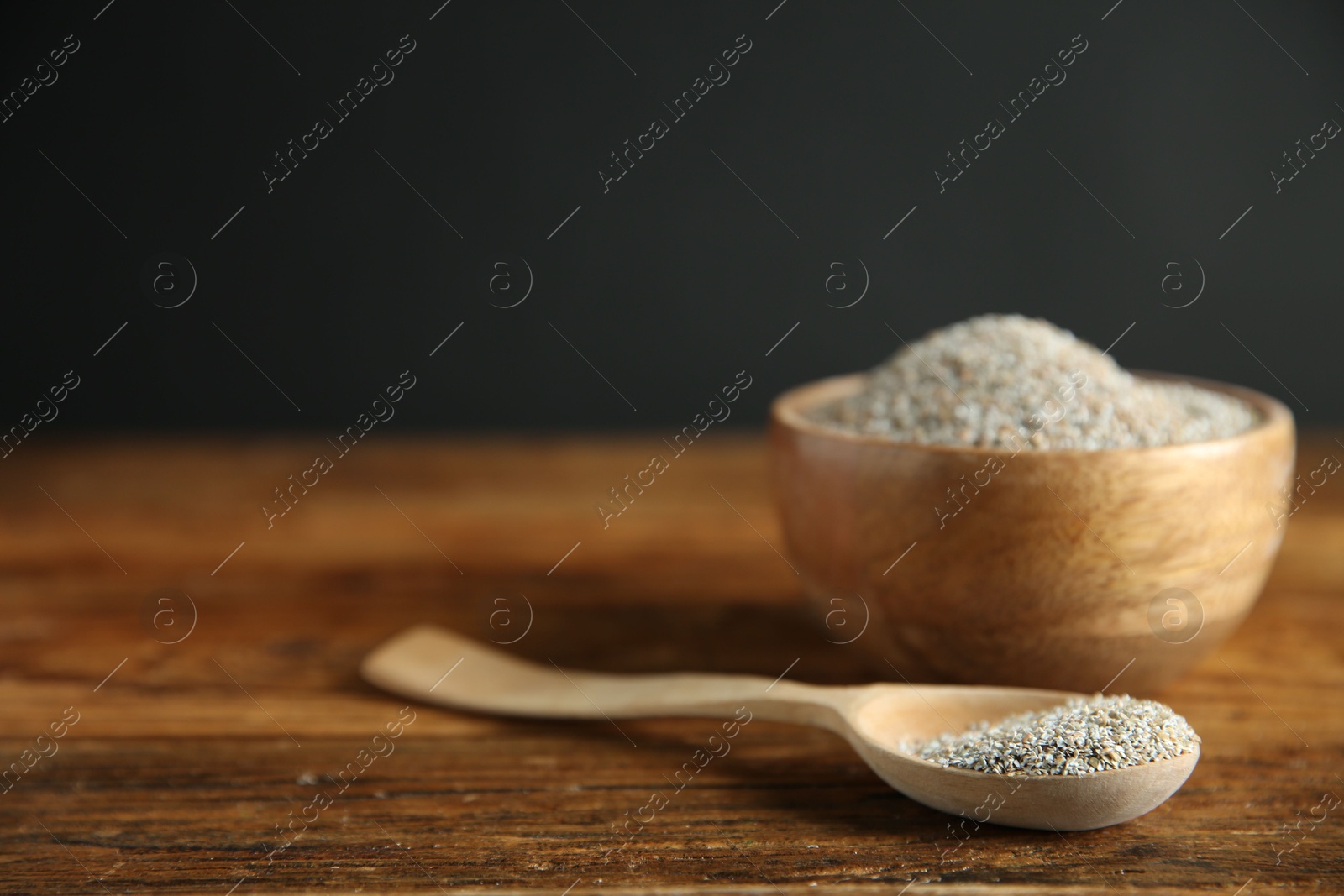 Photo of Fresh rye bran in bowl and spoon on wooden table, closeup. Space for text