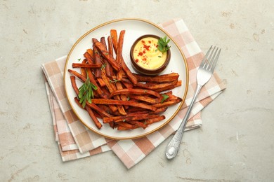 Delicious sweet potato fries with sauce served on light table, top view