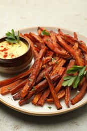 Delicious sweet potato fries with sauce on light table, closeup