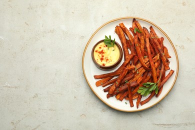 Photo of Delicious sweet potato fries with sauce on light table, top view. Space for text