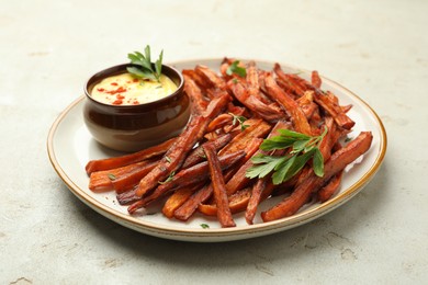 Delicious sweet potato fries with sauce on light table, closeup