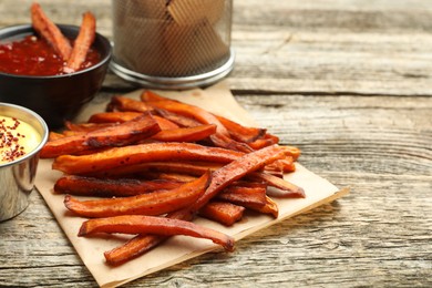 Photo of Delicious sweet potato fries with sauces on wooden table, closeup