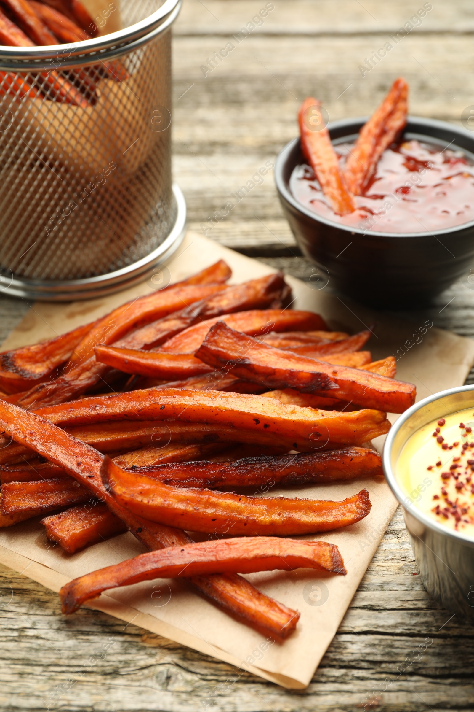 Photo of Delicious sweet potato fries with sauces on wooden table, closeup