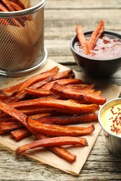 Photo of Delicious sweet potato fries with sauces on wooden table, closeup