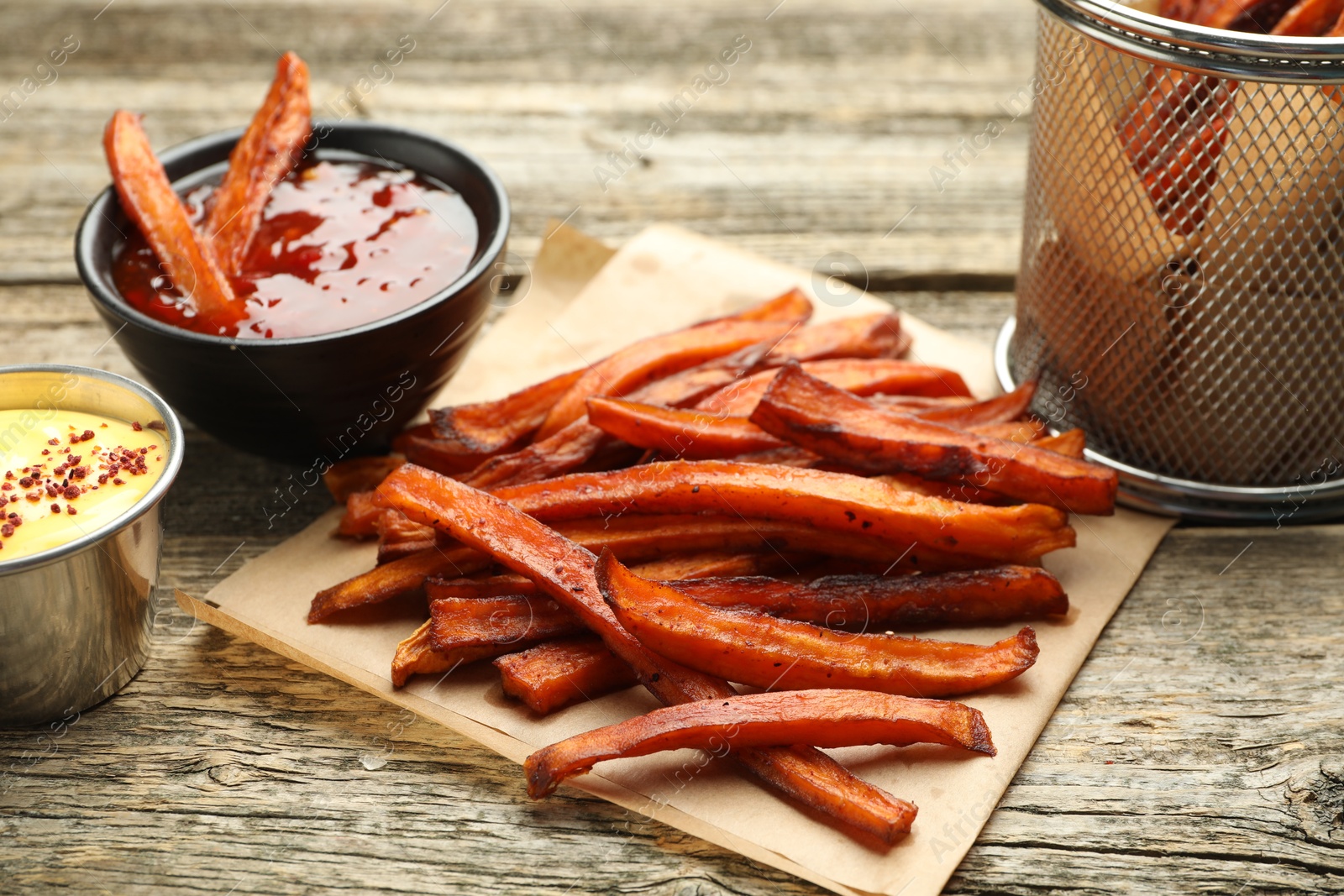 Photo of Delicious sweet potato fries with sauces on wooden table, closeup