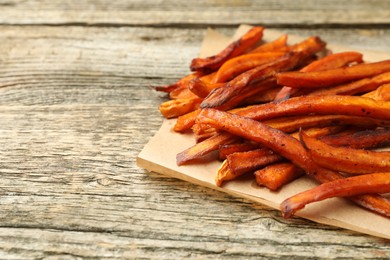 Delicious sweet potato fries on wooden table, closeup. Space for text