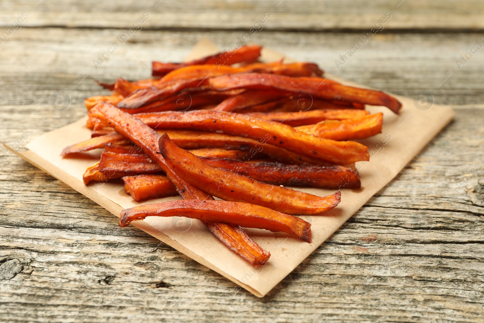 Photo of Delicious sweet potato fries on wooden table, closeup