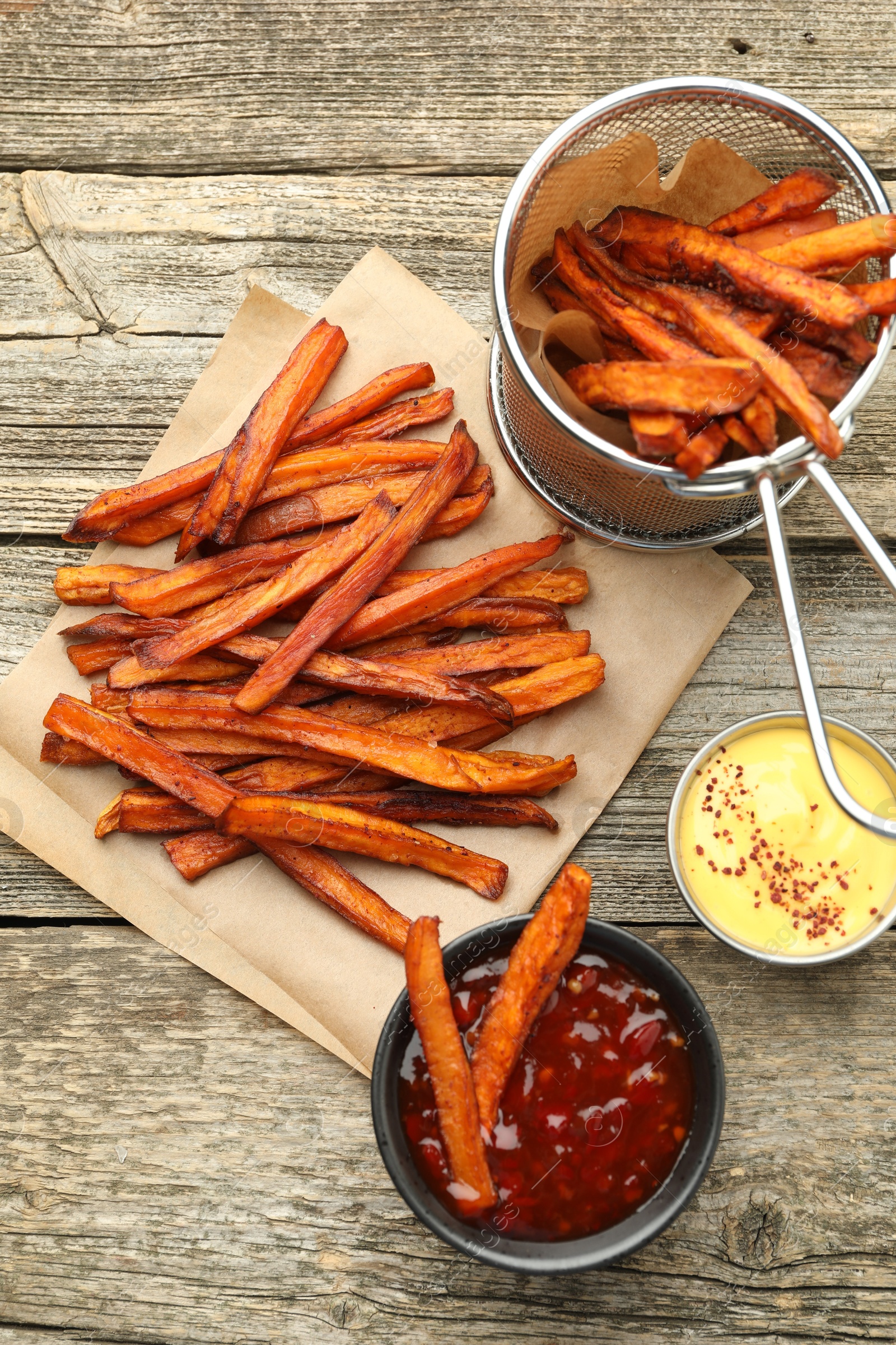 Photo of Delicious sweet potato fries with sauces on wooden table, flat lay