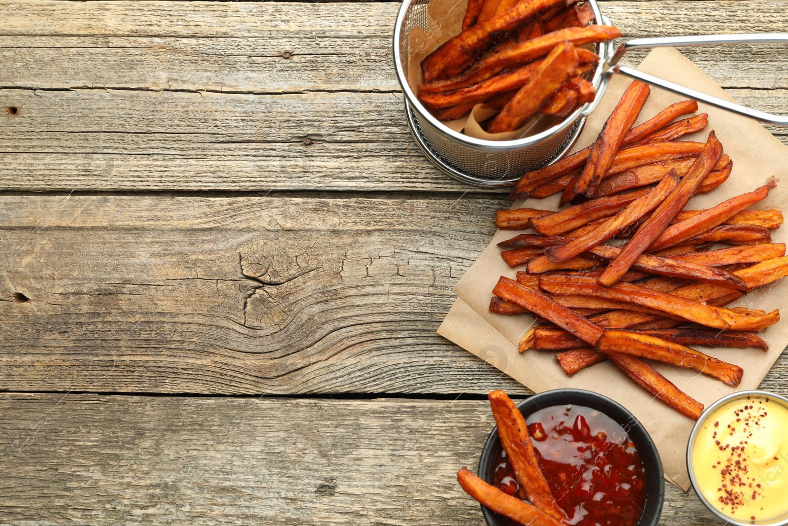 Photo of Delicious sweet potato fries with sauces on wooden table, flat lay. Space for text