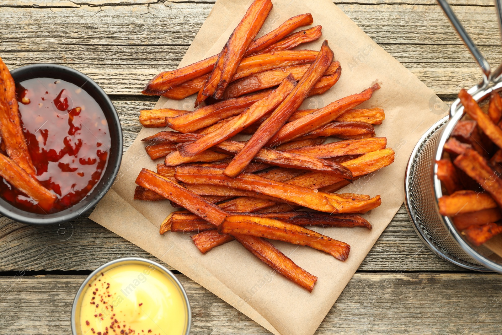 Photo of Delicious sweet potato fries with sauces on wooden table, flat lay