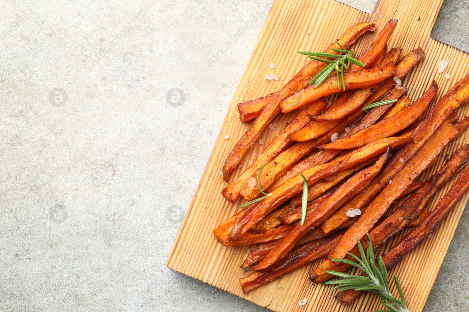 Photo of Delicious sweet potato fries with spices on grey table, top view. Space for text