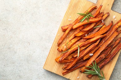 Photo of Delicious sweet potato fries with spices on grey table, top view. Space for text