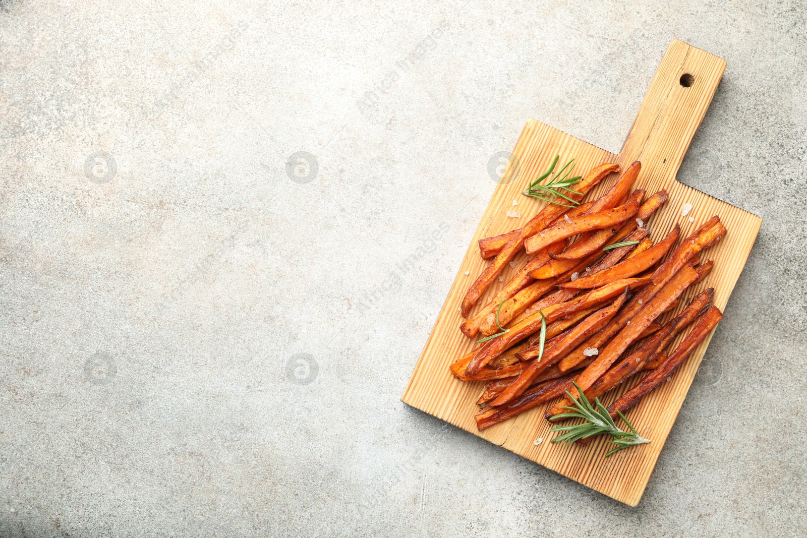 Photo of Delicious sweet potato fries with spices on grey table, top view. Space for text