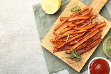 Delicious sweet potato fries with sauce, oil and lemon on grey table, flat lay. Space for text