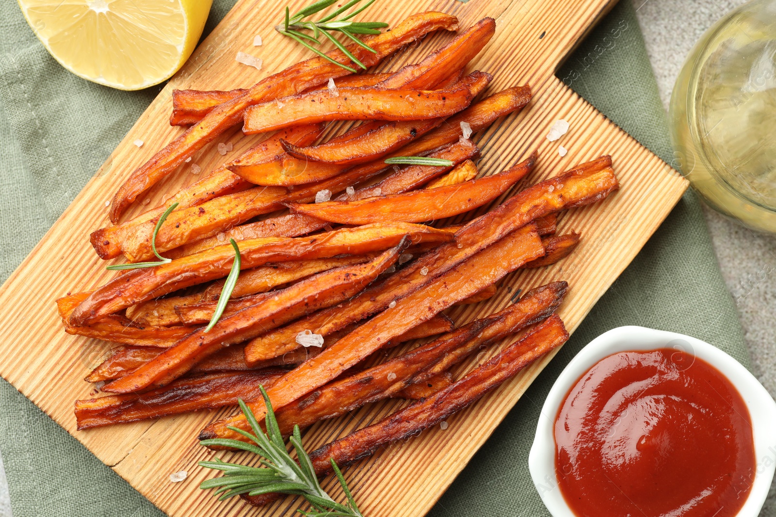 Photo of Delicious sweet potato fries with sauce, oil and lemon on table, flat lay