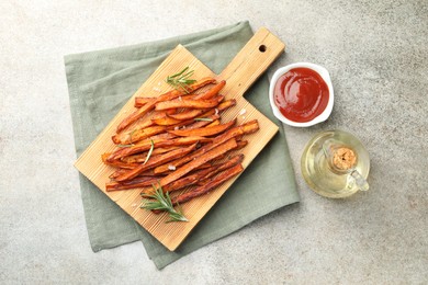 Photo of Delicious sweet potato fries with sauce and oil on grey table, flat lay