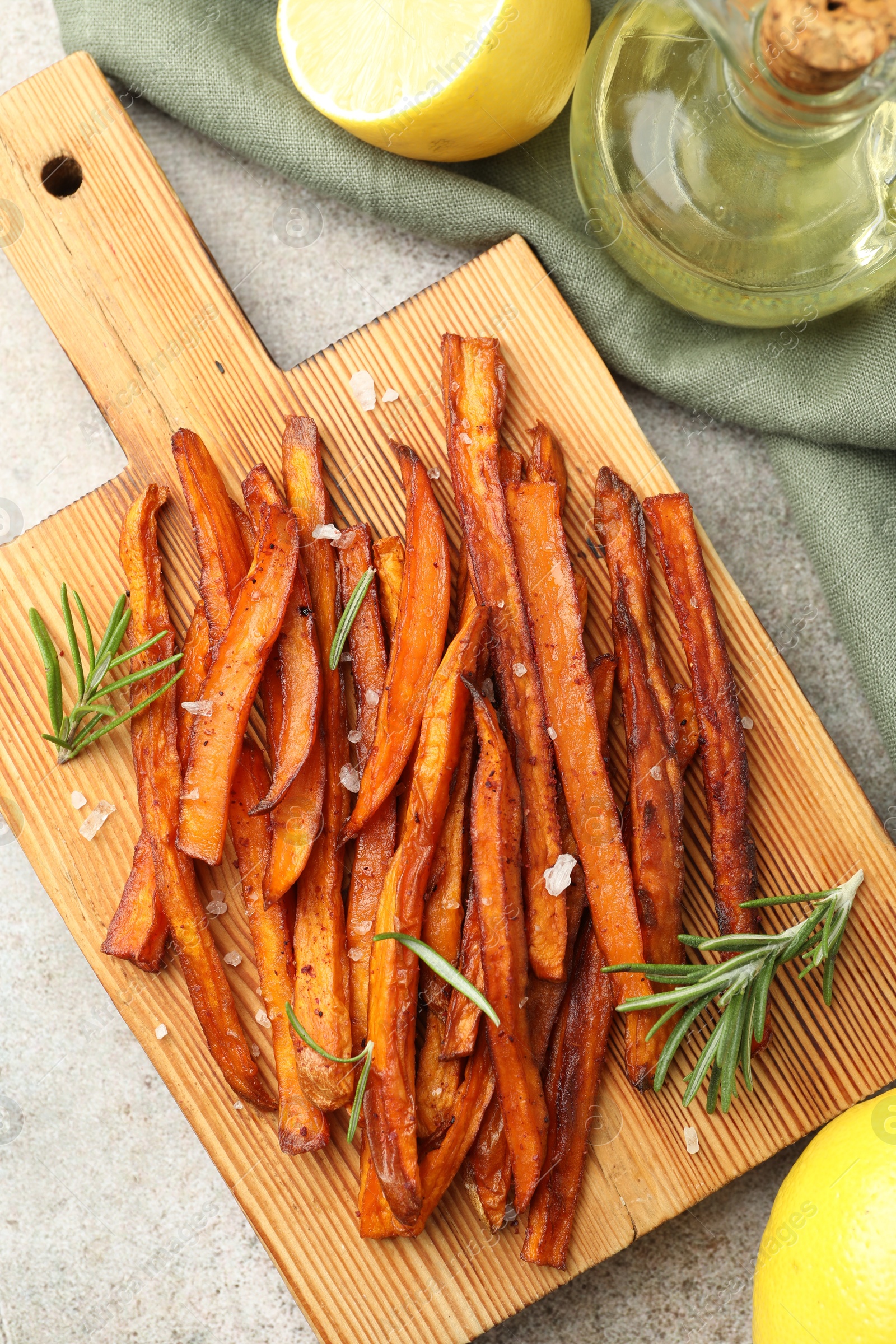 Photo of Delicious sweet potato fries with oil and lemon on grey table, flat lay