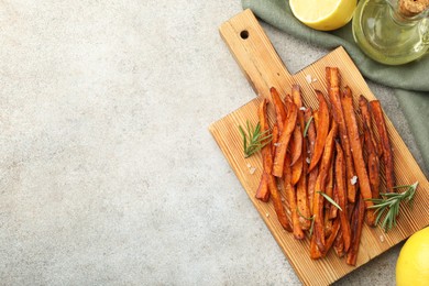 Photo of Delicious sweet potato fries with oil and lemon on grey table, flat lay. Space for text