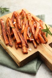 Photo of Delicious sweet potato fries with spices on grey table, closeup