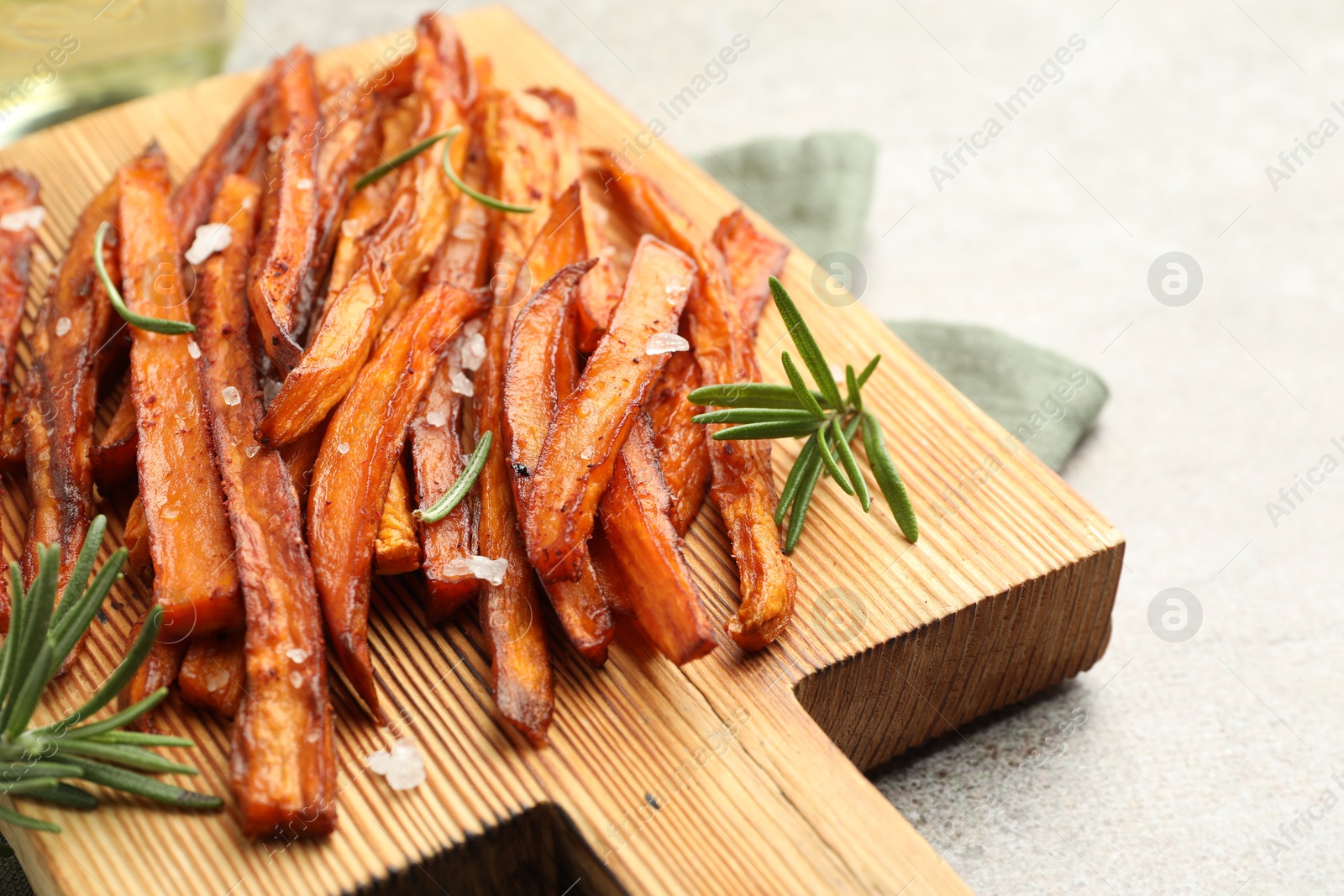 Photo of Delicious sweet potato fries with spices on grey table, closeup