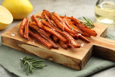 Photo of Delicious sweet potato fries with spices on grey table, closeup