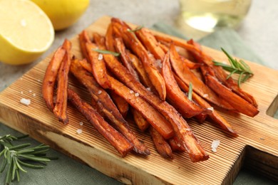 Photo of Delicious sweet potato fries with spices on grey table, closeup