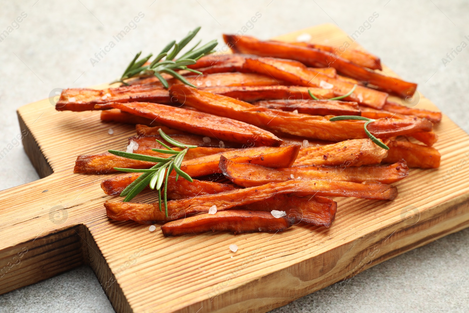 Photo of Delicious sweet potato fries with spices on grey table, closeup