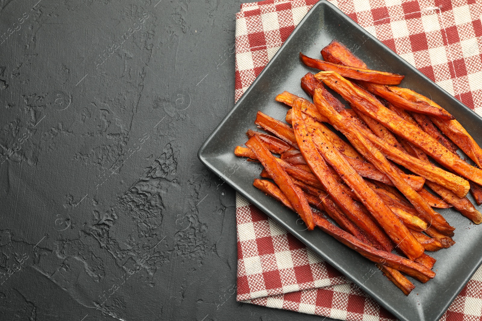 Photo of Delicious sweet potato fries on black table, top view. Space for text