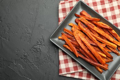 Delicious sweet potato fries on black table, top view. Space for text