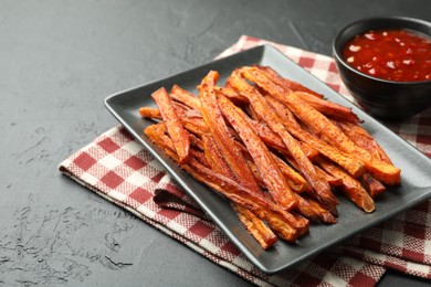 Photo of Delicious sweet potato fries with sauce on black table, closeup