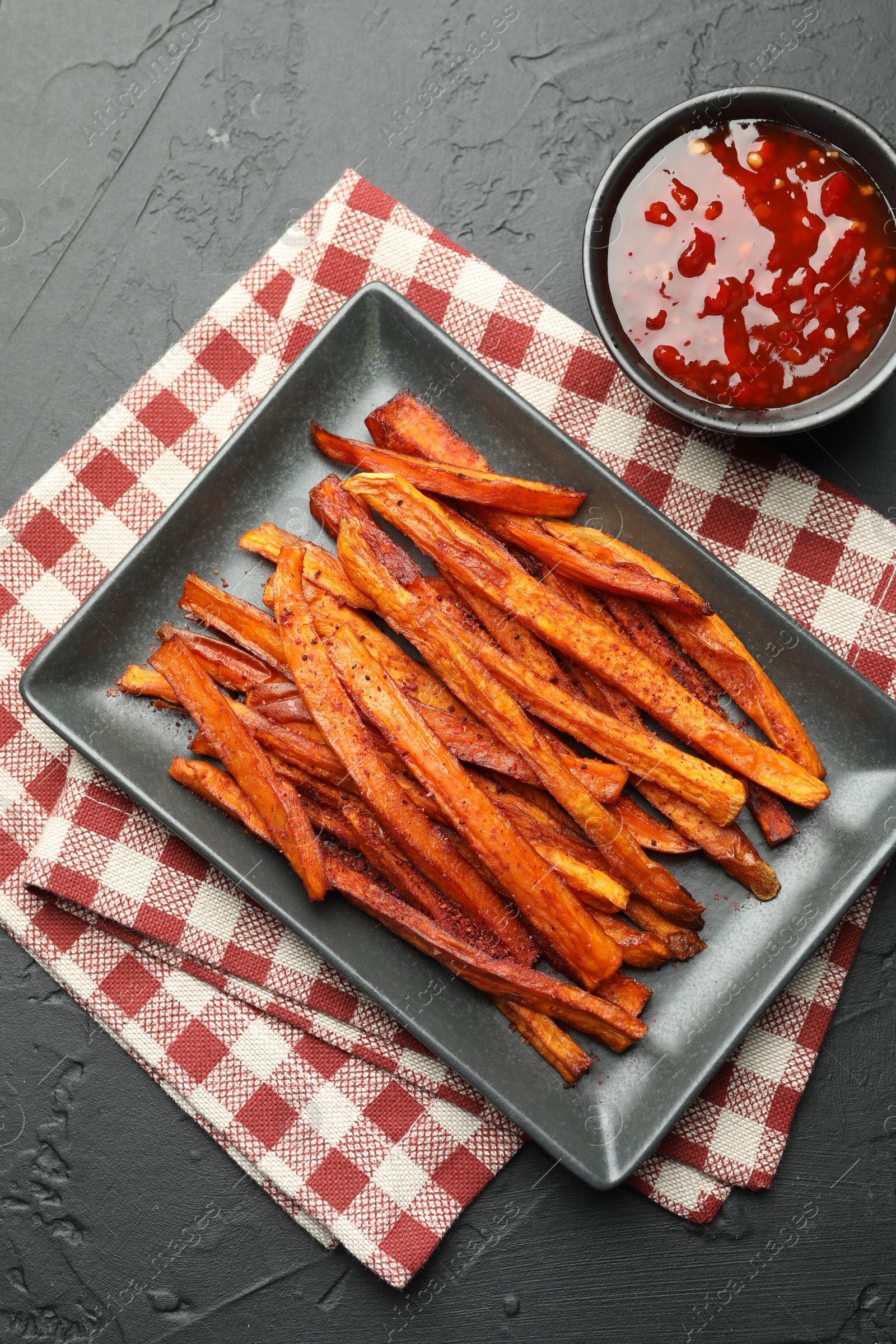 Photo of Delicious sweet potato fries with sauce on black table, top view