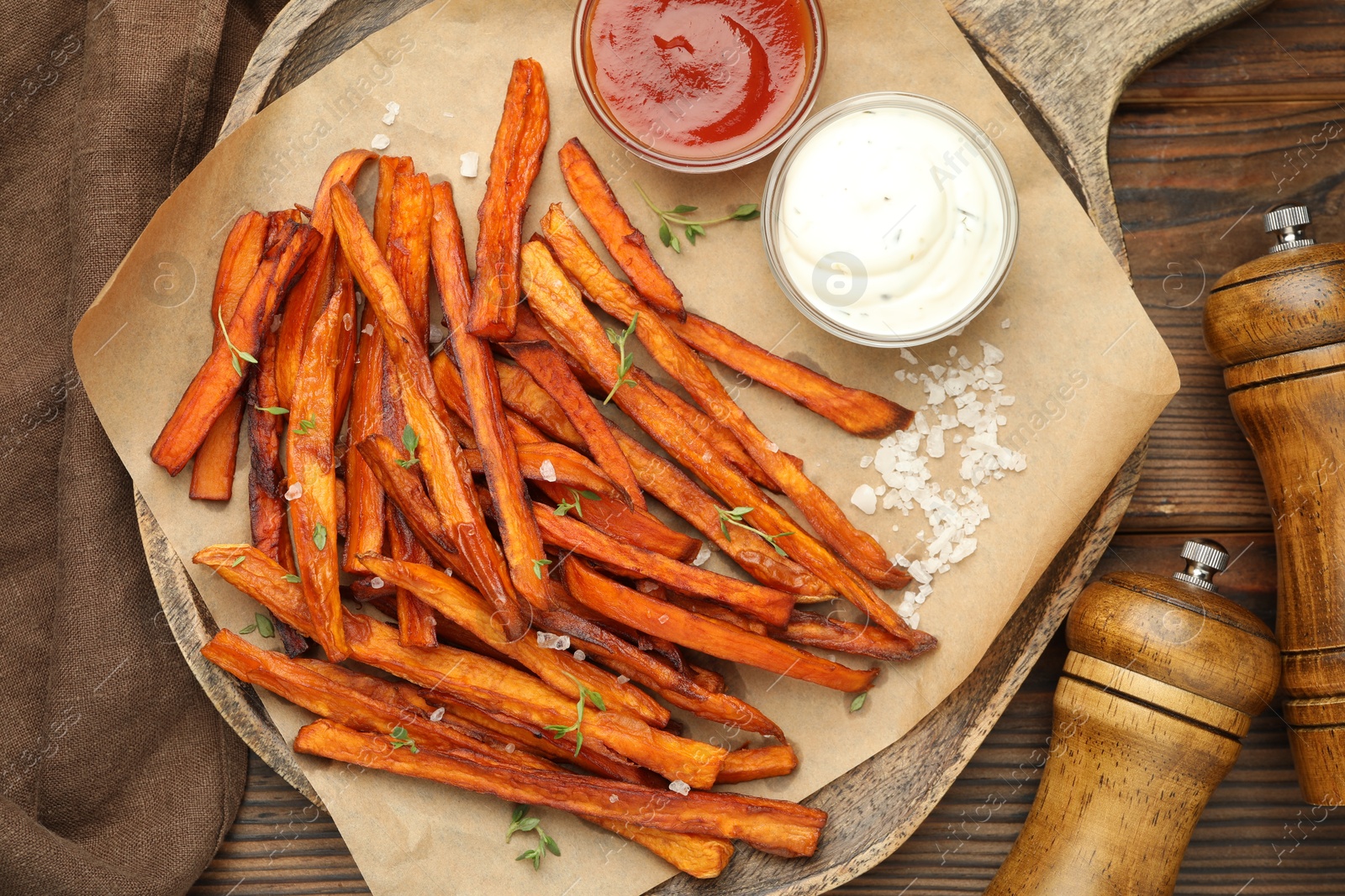 Photo of Delicious sweet potato fries with sauces and spices on wooden table, flat lay