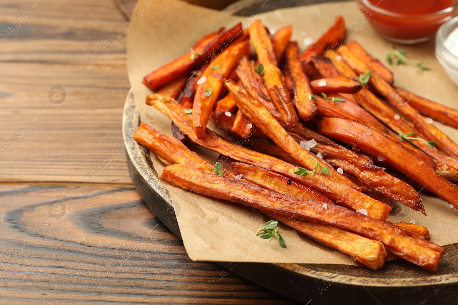 Photo of Delicious sweet potato fries served on wooden table, closeup