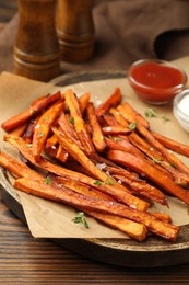 Photo of Delicious sweet potato fries with sauces and spices on wooden table, closeup