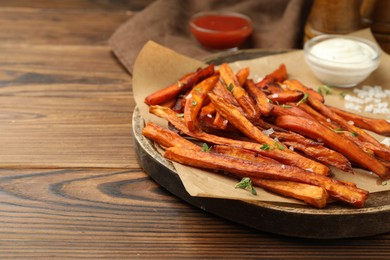 Photo of Delicious sweet potato fries served on wooden table, closeup