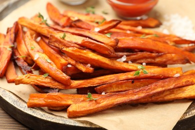 Delicious sweet potato fries served on wooden table, closeup