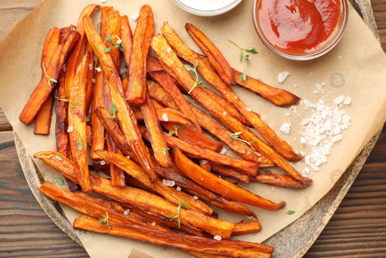 Photo of Delicious sweet potato fries served on wooden table, closeup