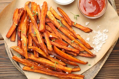 Photo of Delicious sweet potato fries served on wooden table, closeup